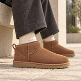UGG Classic Ultra Mini Chestnut in cognac suede gedragen op natuurstenen bestrating — ROVARO foto 2 4349b7c6bd0af7df