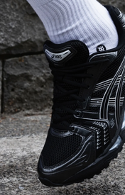 Asics Gel Kayano 14 Black Pure Silver - Zwart — gedragen, detail zonder gezicht — brongetrouwe fotobewerking 2026-10-02